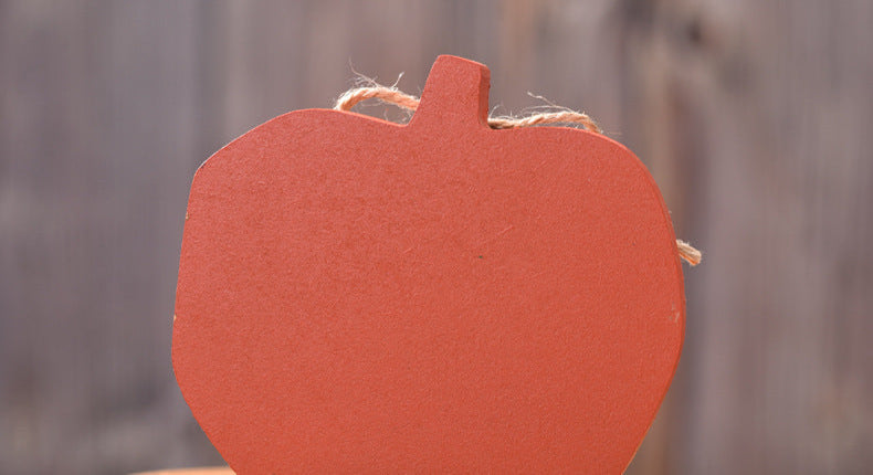 Wooden pumpkin decoration with a smiling face on a wooden surface.