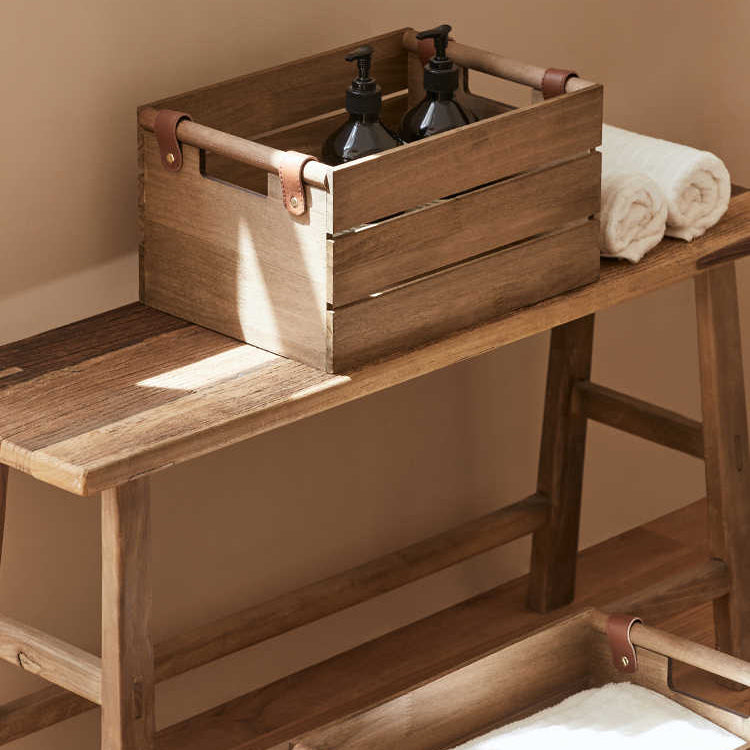 Wooden crate with bottles on a wooden bench against a beige wall