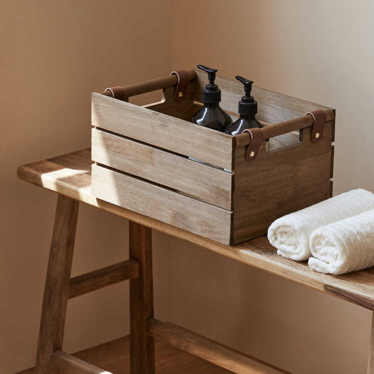 Wooden crate with bottles and towels on a wooden table against a beige wall