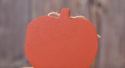 Wooden pumpkin decoration with a smiling face on a wooden surface.
