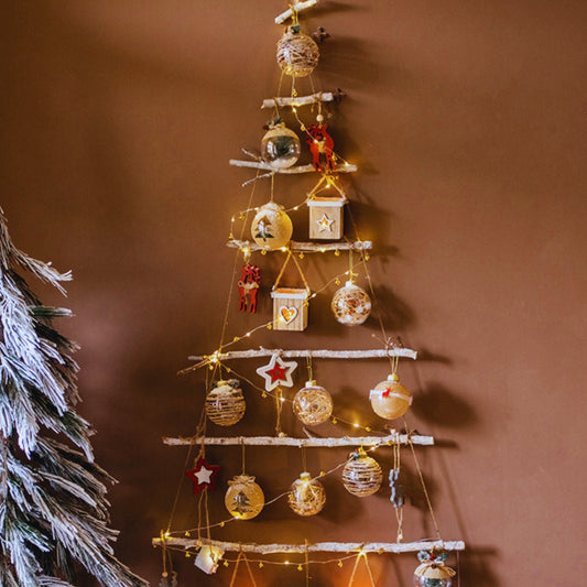Decorative wall-mounted Christmas tree with ornaments and lights on a brown wall.